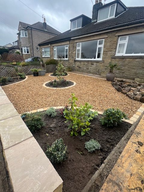 Golden gravel garden with flower beds edged with tumbled cobbles